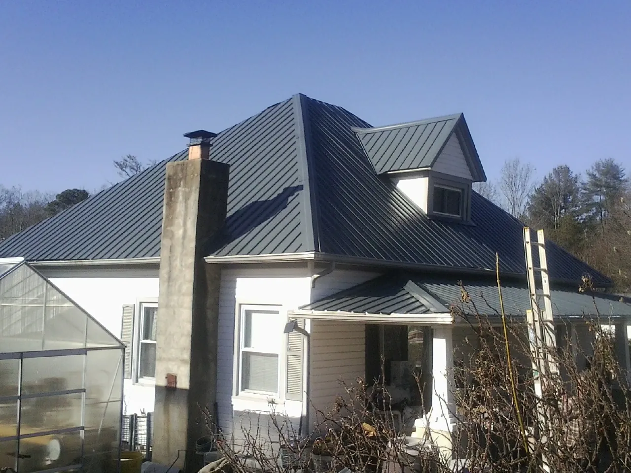 Dark blue standing seam metal roof on a white farmhouse with dormer — Slate & Tile Roof Repair by Roofing Brothers in Pine City