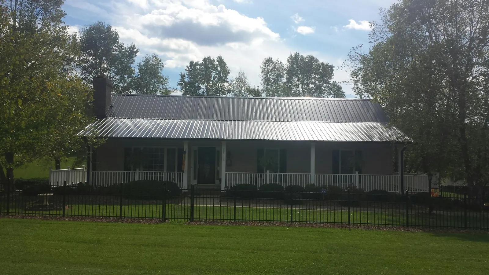 Gray metal roof on a brick ranch with a full width front porch — Gutter Guard Installation work by our crew in Pine City